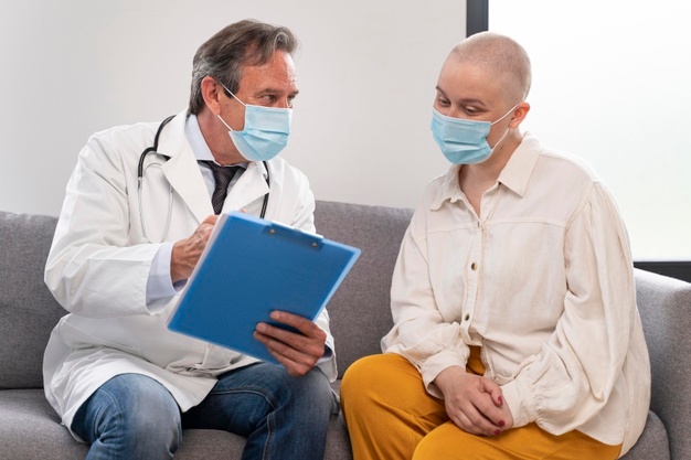 Mulher branca com câncer de mama em consulta com um médico homem branco.