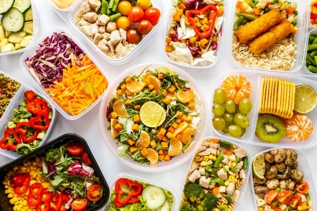 A imagem exibe uma mesa com diversos tipos de alimentos associados a alimentação saudável.