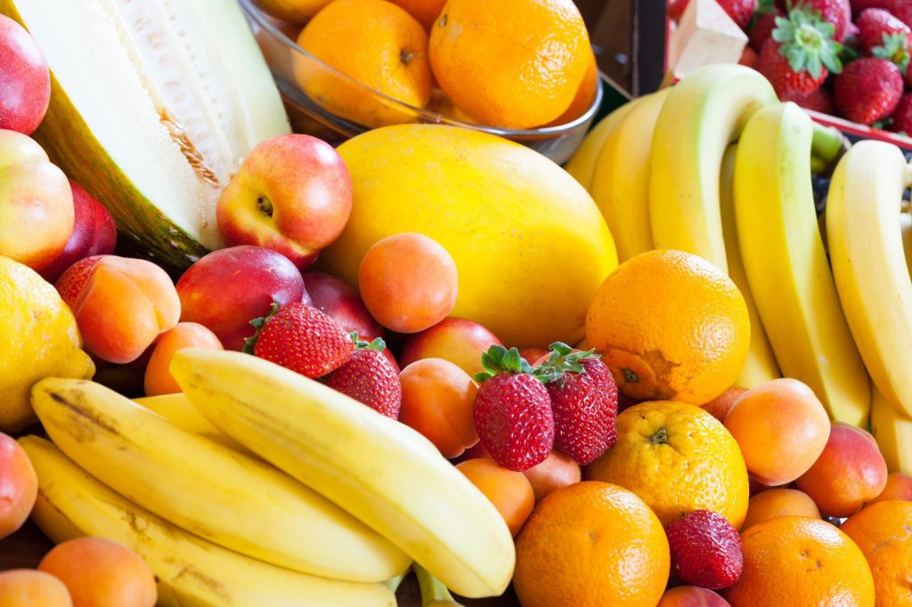 Diversidade de frutas como melão, maçã, banana, morango, laranja e pêssego