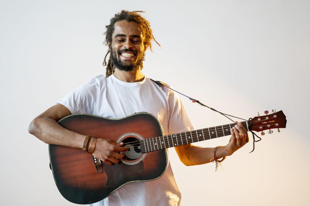 Homem sorridente de camisa branca tocando violão