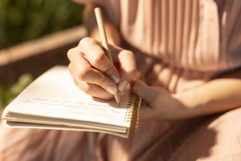 mulher escrevendo páginas em seu diário a lápis